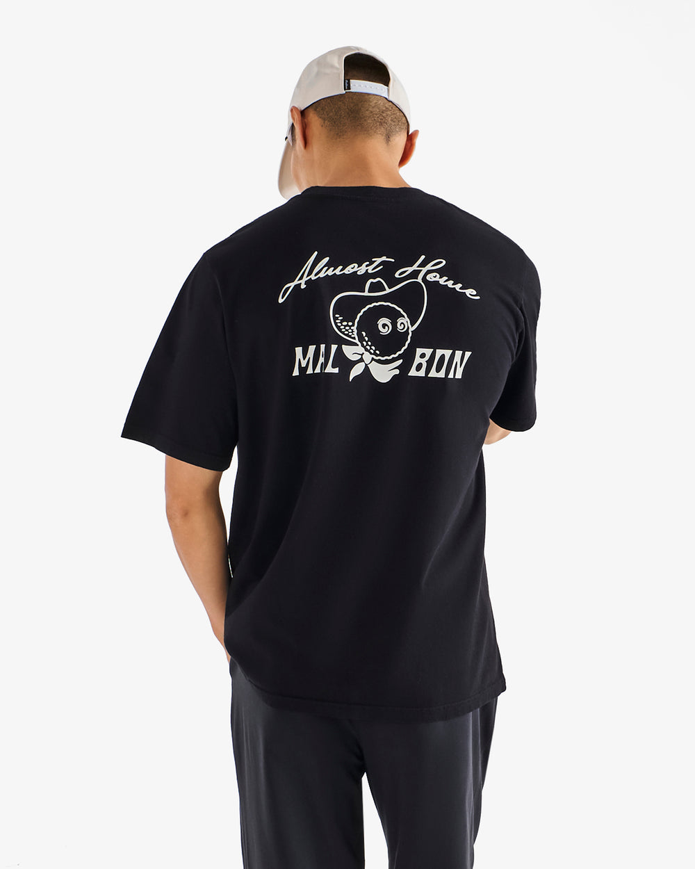 Person wearing a black t-shirt with white text and graphics on the back, standing against a white background.